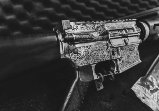 A black gun that has been customized through laser engraving sits in a gun case.