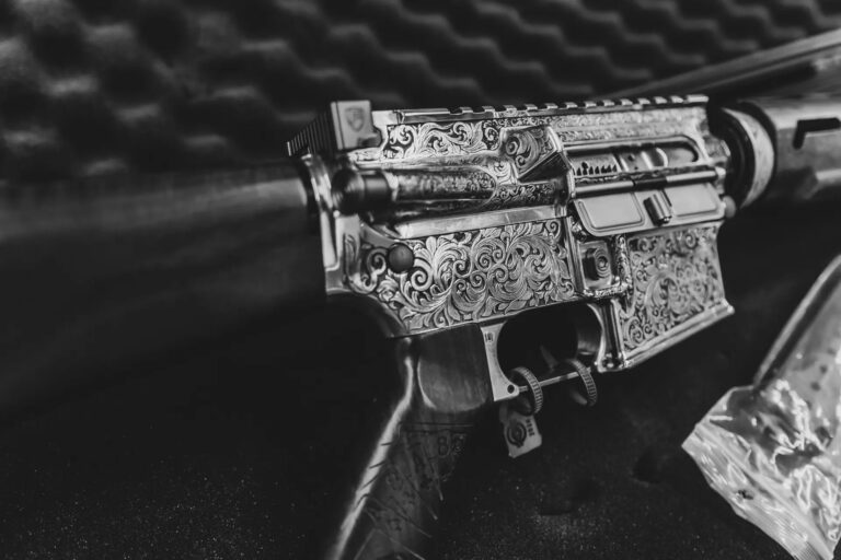 A black gun that has been customized through laser engraving sits in a gun case.
