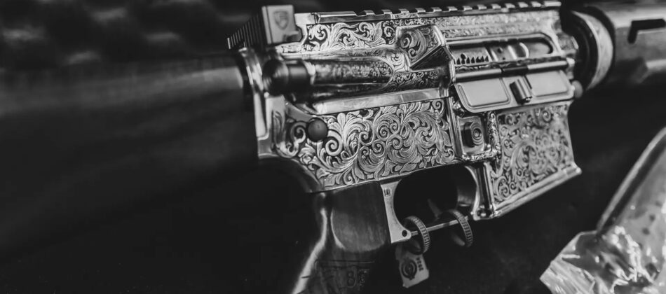 A black gun that has been customized through laser engraving sits in a gun case.