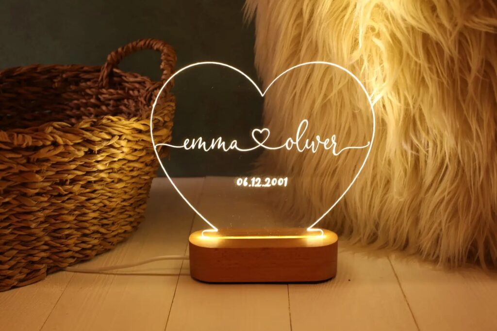 A light-up glass decoration featuring the names and wedding date of a married couple sit in front of a basket and a decorative fur piece.